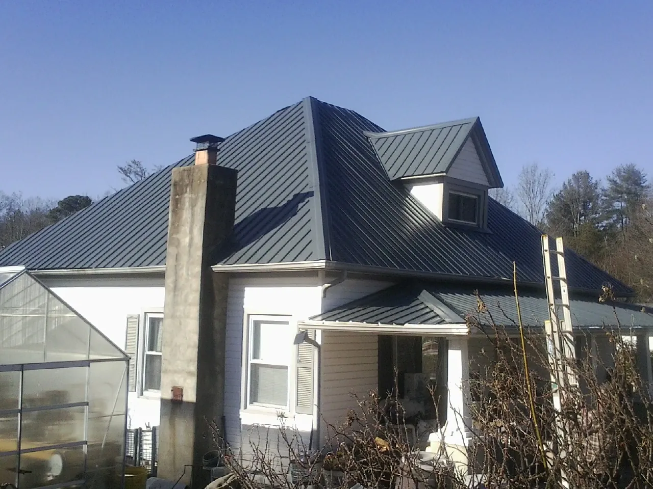 Dark blue standing seam metal roof on a white farmhouse with dormer — Slate & Tile Roof Repair by Roofing Brothers in Sandia Park