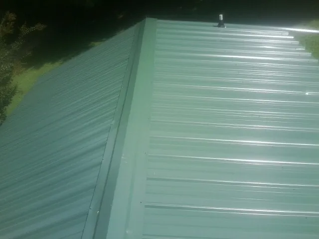 New green metal panels meeting at the ridge of a roof — Flat Roof Repair work by our crew in Sandia Park