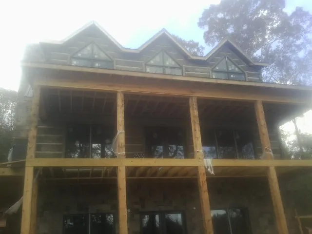Dormers and porch framing on a large log home under construction — Roof Coating work by our crew in Sandia Park