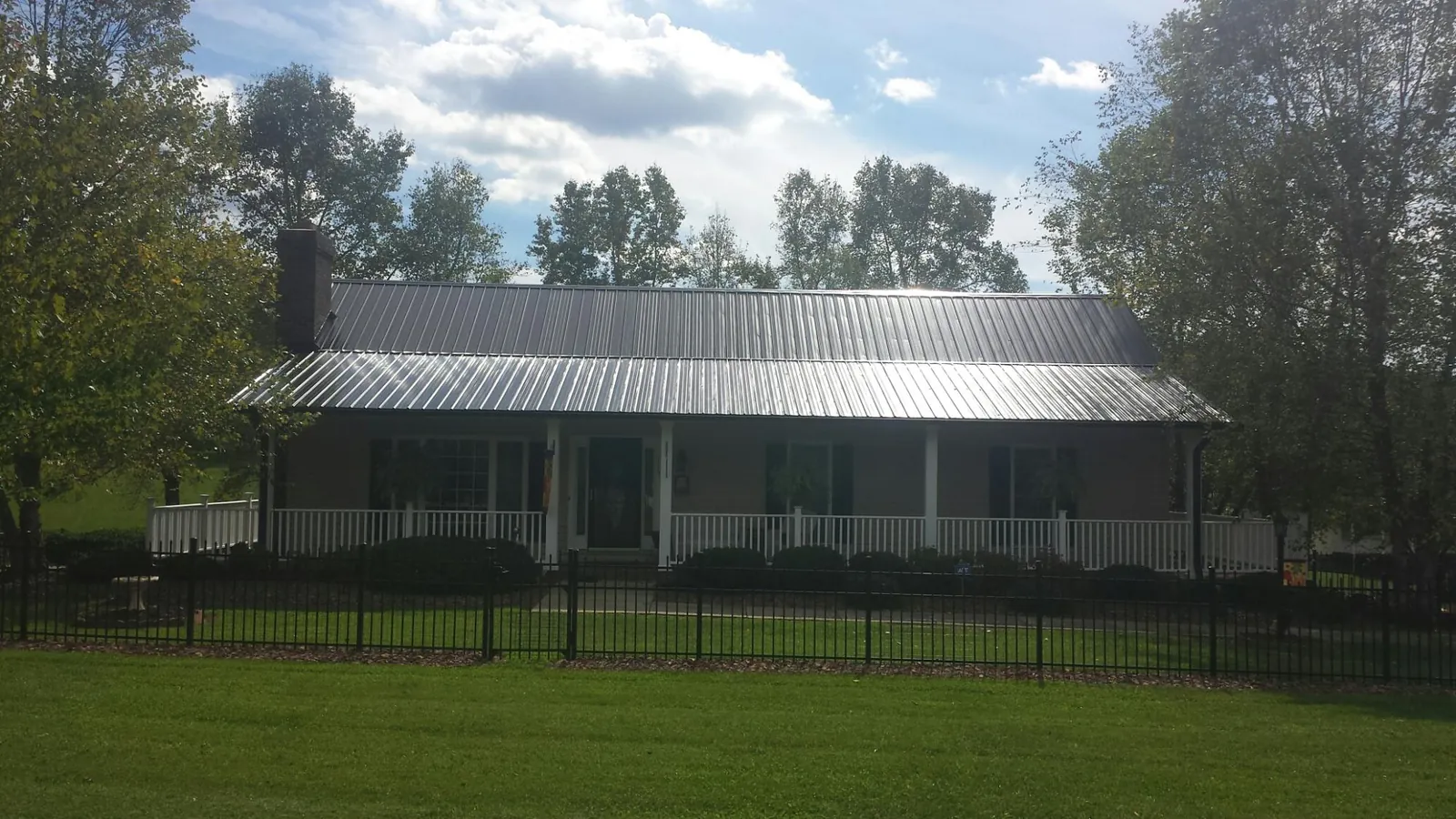 Gray metal roof on a brick ranch with a full width front porch — Gutter Guard Installation work by our crew in Sandia Park