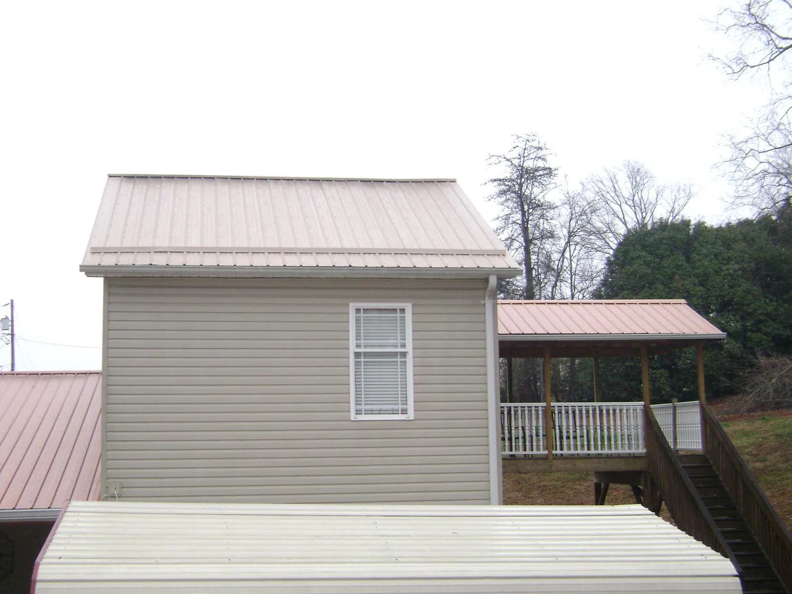Tan metal roofs on a two story addition and attached porch, from a Roof Replacement job in Sandia Park