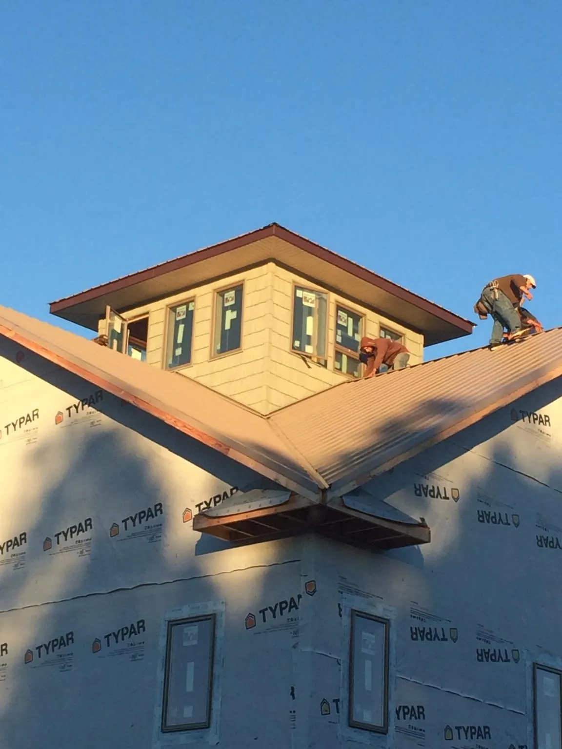 Roofers working around a rooftop cupola on a new metal roof at sunset — Roof Waterproofing in Sandia Park by Roofing Brothers